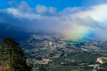 Landscape at Cartago, Costa Rica. A Cypress tree, a hill and the start of a rainbow.