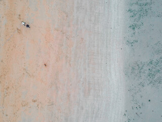 Plage vue du ciel, photo prise en drone. Personne qui promène son chien. Mer turquoise et sable jaune orange. Vue aérienne de la plage. 