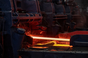 Red-hot metal billet on the roller table of a rolling mill © nordroden