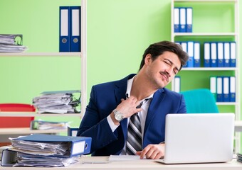 Businessman unhappy with excessive work sitting in the office