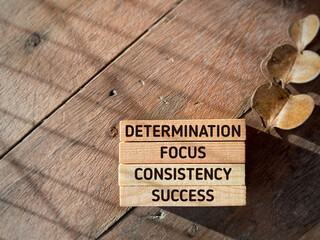 Inspirational and motivational quote of determination focus consistency success. Text on wooden blocks background. Stock photo.