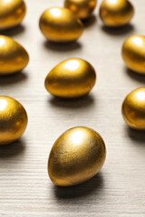 Many golden eggs on white wooden table
