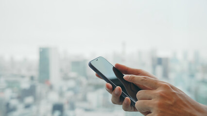 都市を背景にスマートフォンを使う女性