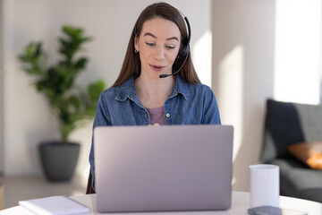 Caucasian woman at home remote working on laptop computer talking to her colleague