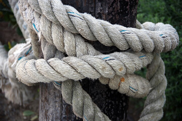 Close-up view of a heavy rope tied around a wooden post