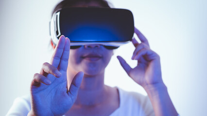 Young woman wearing virtual reality headset touching air during the VR on Metaverse experience. VR (virtual reality), Technology, Video Game and Metaverse Concept.