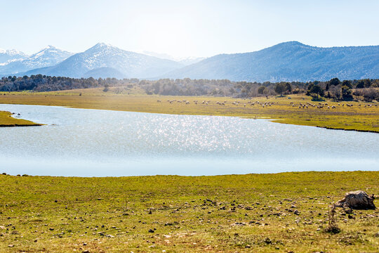 View of Lake Beysehir, reflection, mountains and sun. The lake is fed by streams flowing from the Sultan Mountains and the Anamas Mountains. The water level in the lake often fluctuates by year.