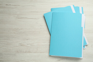 Turquoise files with documents on white wooden table, top view. Space for text