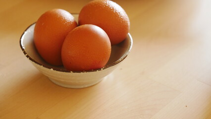 close up of three eggs in a small bowl on a wooden table
