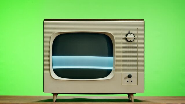 Old television with grey interference screen on chroma green background. Close-up of vintage tv, nostalgia. Gray noise screen and glitches.