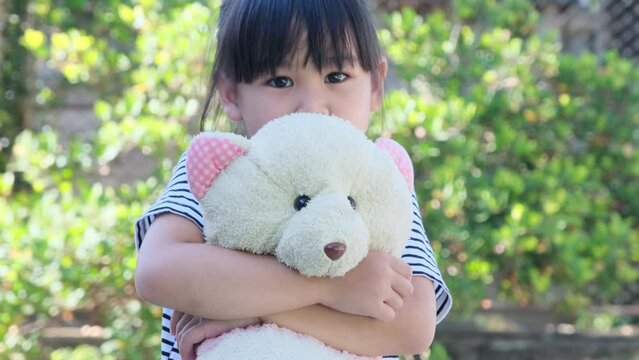 Cute little girl holding and embracing her doll. Children playing with stuffed toys in the front yard.