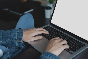 Casual business woman using, working on laptop computer, typing on keyboard with blank screen while sitting on sofa in living room at home office. mockup template