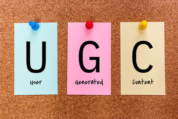 Conceptual 3 letters keyword UGC (User Generated Content) on multicolored stickers attached to a...