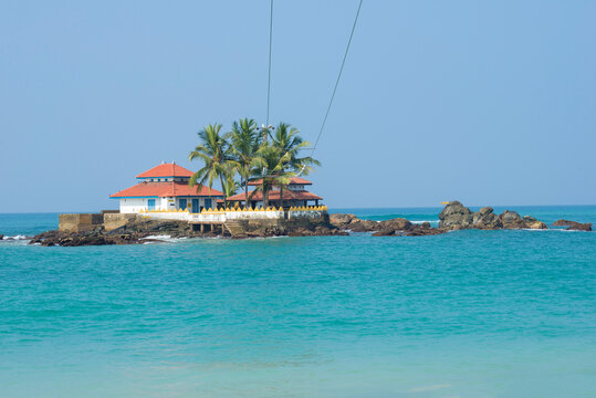 View of the ancient Buddhist temple Seenigama Muhudu Viharaya on the island on a sunny day. Peraliya, Sri Lanka