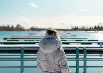 Girl admiring the view of boating dock on body of water on a warm winters day