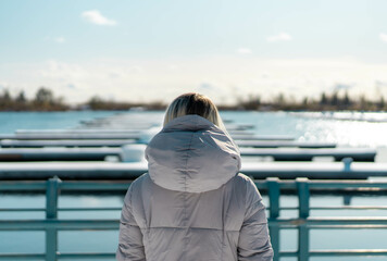 Girl admiring the view of boating dock on body of water on a warm winters day