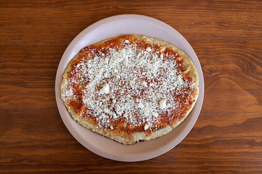 An original Memela with red sauce and cheese served on a plastic plate in Tonanzintla town, Puebla, Mexico.