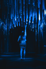 Girl reaching to touch streamers down the dark hall of a local art exhibit
