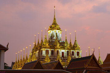 Naklejka premium Top of the old Loha Prasat pagoda of Wat Ratchanatdaram Woravihara Buddhist temple against the evening sky. Bangkok, Thailand