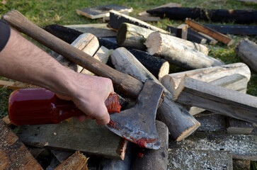 we make special effects of bloody details with ketchup or tomato puree. just a few drops of red fluid and the stuntman has a bloody tool like horror. man splashes an ax on a pile of wood with a bottle