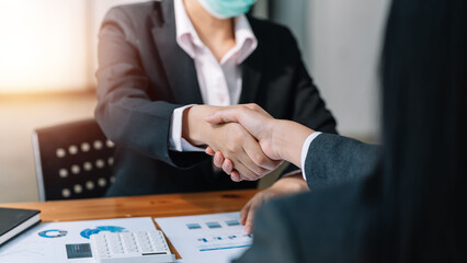 Business people collaboration deal shaking hands at meeting and financial paper graph on desk in modern office.