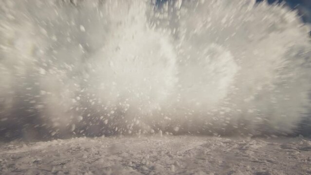 Professional rider shredding down the snowy ski slope. Covers the camera with snow. Splash snow into the lens. Snowboarder carves on the ski slope. Extreme Winter sports at the resort. Fun twist