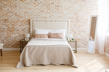 A room in light loft stile with brick wall and light furniture. Comfortable bedroom. A combination of modern and old. Join the glass and brick. Modern lamp on a glass bedside table. 