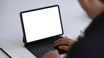View over shoulder businessman working with computer tablet at office desk.