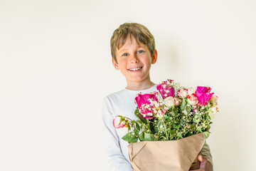 Portrait of an eight-year-old Caucasian boy with a bouquet of flowers in his hands, looking...