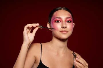 Obraz premium Portrait of beautiful young woman makeup emotions cosmetics hair care mascara pink background unaltered