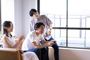 家でテレビゲームをする若い男女
