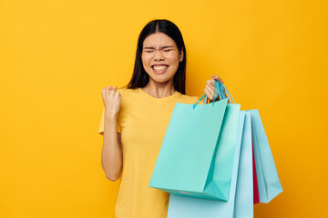 Fototapeta premium woman with Asian appearance in a yellow T-shirt with multicolored shopping bags studio model unaltered