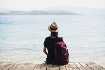 Young woman with backpack looking at the sea, relaxation, vacations, travel lifestyle, summer fun,...