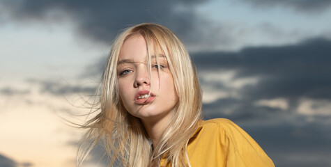 Fototapeta premium Portrait of young woman outdoor. Romantic girl with beauty face. Sensual blonde woman, beautiful girl on dramatic sky.