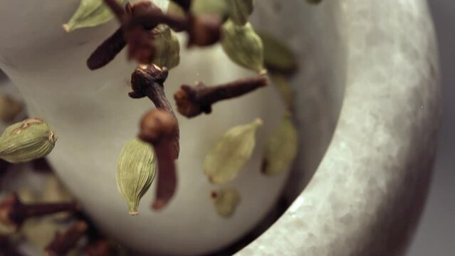 Granite mortar and Cardamom and Cloves Spice Species Falling in Slow Motion