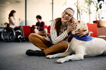 Happy businesswoman embraces her Labrador therapy dog and having fun in office. - obrazy, fototapety, plakaty