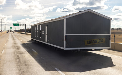 Mobile house transportation. Transporting portable home on the highway in Texas. Oversize logistics, semi truck carries a large prefabricated house on semi trailer. Trucking jobs and real estate