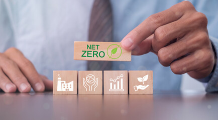 Hand puts wooden cubes with net zero icon in Net zero on grey background. Net zero by 2050. Carbon...