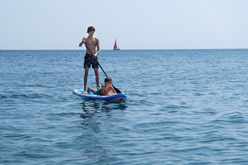 A young sports man with a child sails on a sup in the sea. Healthy lifestyle concept