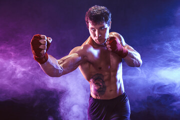 Half length of athlete shirtless boxer who preparing for fight on smoke background. Sport concept