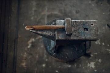 Blacksmith's hammer on metal anvil at forge. Overhead view