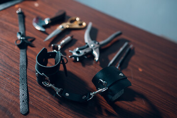 Tanner tools and leather handcuffs on table.