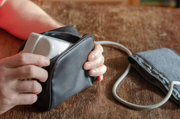The man's hands are placed in a black pouch digital blood pressu