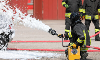 firefighters use a jet of foam to put out the fire after the car accident