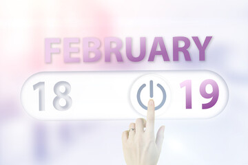 February 19th. Day 19 of month, Calendar date.Hand finger switches pointing calendar date on sunlight office background. Winter month, day of the year concept.