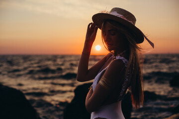 Silhouette of a girl in a hat on the background of the dawn sun close-up. Vacation, beach holiday concept.