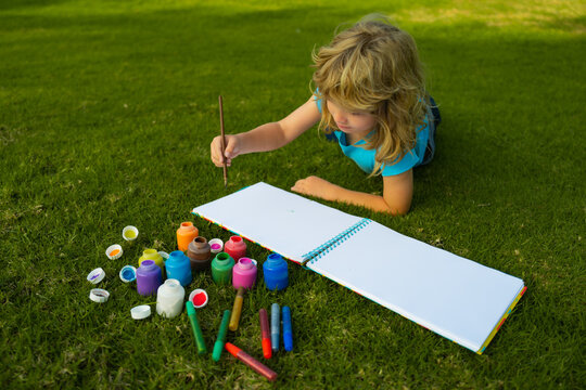 Child boy enjoying art and craft drawing in backyard or spring park. Children drawing draw with pencils outdoor.