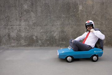 Funny businessman driving retro pedal car outdoor