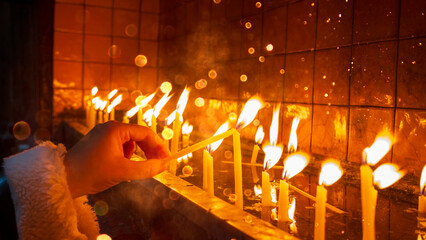 Fototapeta na wymiar St. Antoine Church. Making a wish by lighting a candle. Praying women.