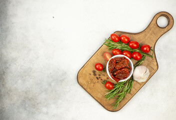 Sun dried tomatoes with fresh herbs, spices, tomatoes and garlik. Grey background. top viewer